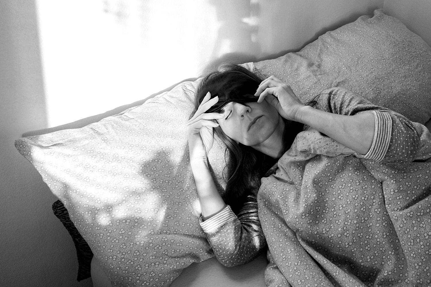 woman with a migraine laying in bed with eye mask